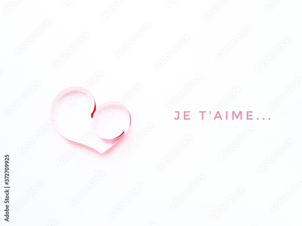 The heart is made of red paper on a white background. Text I love you in French. Valentine's Day.