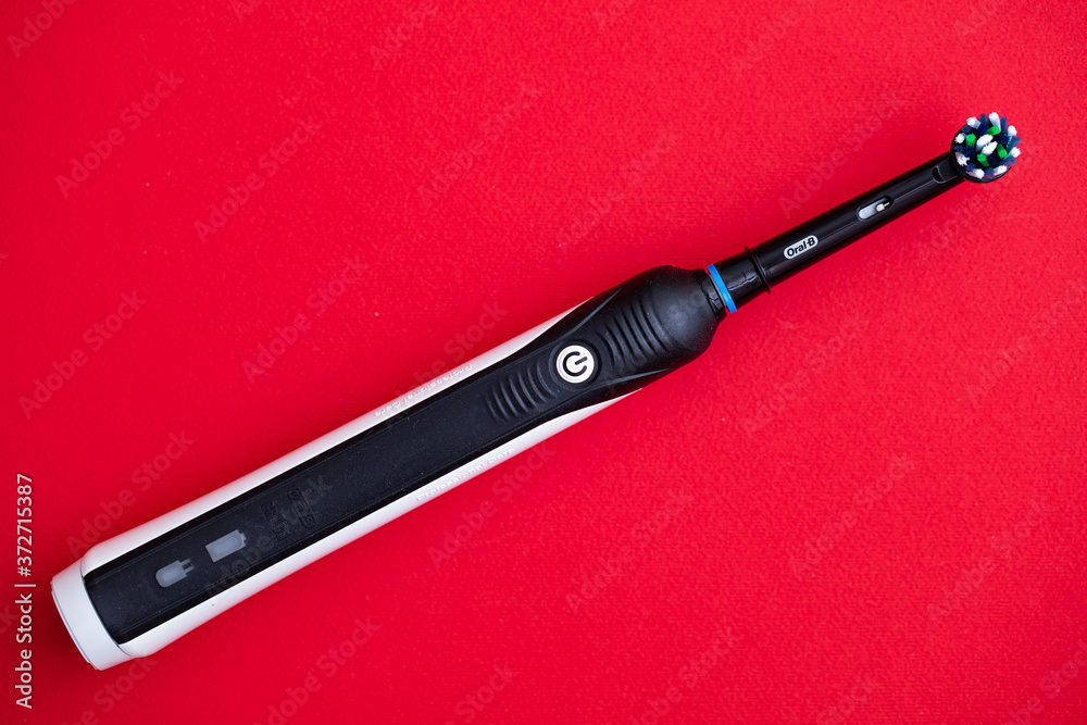 Closeup of Electric toothbrush Oral-B Cross Action PRO 750 black edition on  red background Stock Photo | Adobe Stock