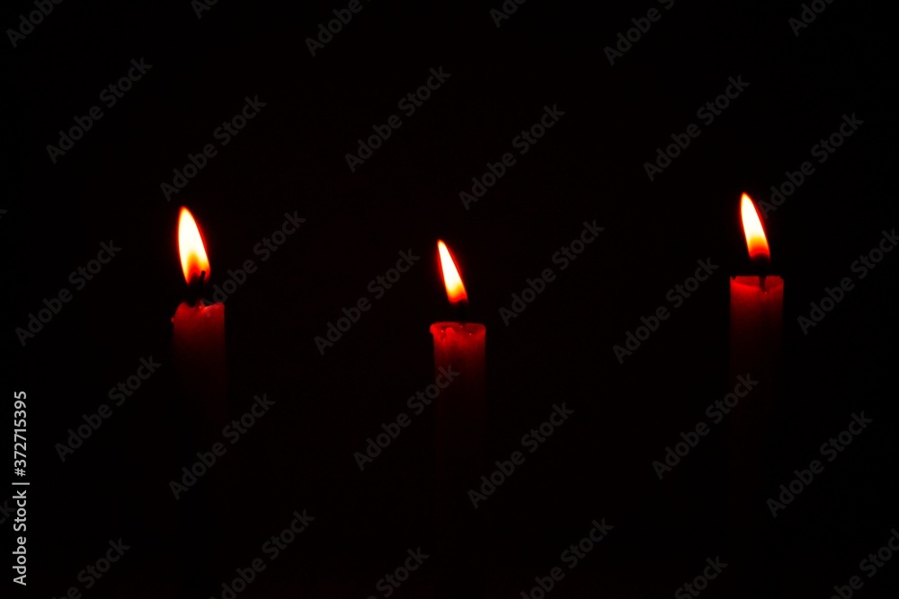 White Candles Burning in the Dark with lights glow, the burning candle's flame in the dark background, a symbol of the Christian faith, Candles burning in the Dark with lights glow White Candles Burning in the Dark with lights glow, the burning candle's flame in the dark background, a symbol of the Christian faith, Candles burning in the Dark with lights glow