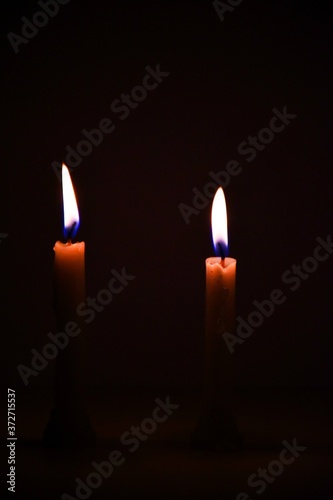 White Candles Burning in the Dark with lights glow, the burning candle's flame in the dark background, a symbol of the Christian faith, Candles burning in the Dark with lights glow