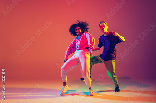 Wallpaper Mural Drive in motion. Stylish man and woman dancing hip-hop in bright clothes on green background at dance hall in neon light. Youth culture, movement, style and fashion, action. Fashionable portrait. Torontodigital.ca