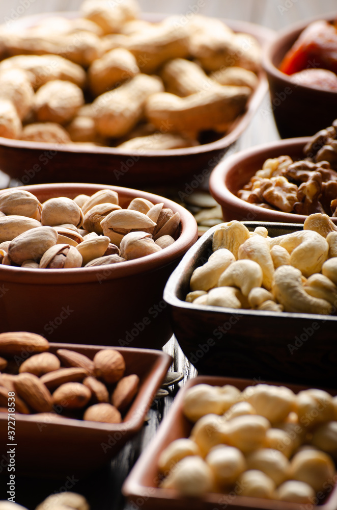 Assorted nuts and seeds in clay bowls on wooden kitchen table Assorted nuts and seeds in clay bowls on wooden kitchen table