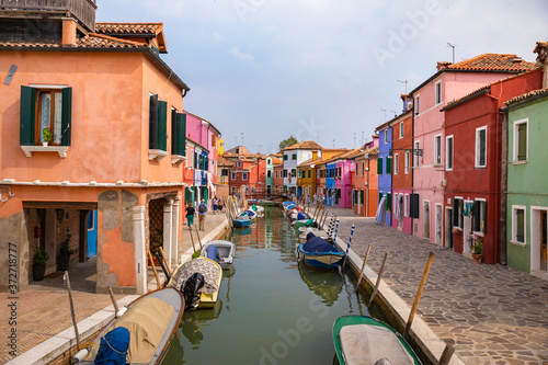 Burano, Italy - 09-18-2019 Colorful houses by canal in Burano, Italy. Burano is an island in the Venetian Lagoon and is known for its lace work and brightly colored homes.