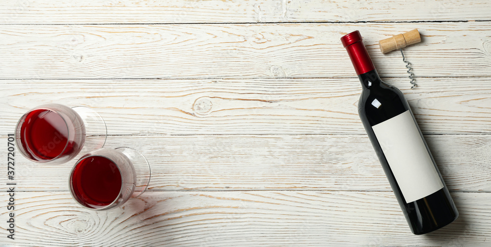 Corkscrew, bottle and glasses of wine on wooden background, space for text