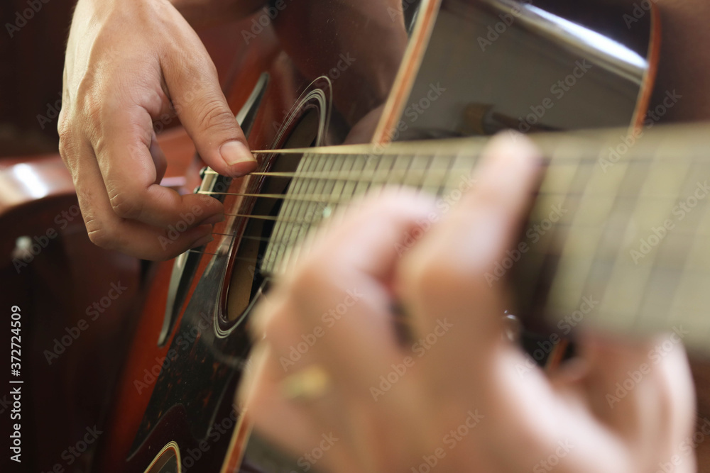 close up of man's hand playing guitar