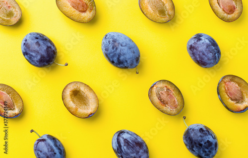 blue plums on yellow background top view
