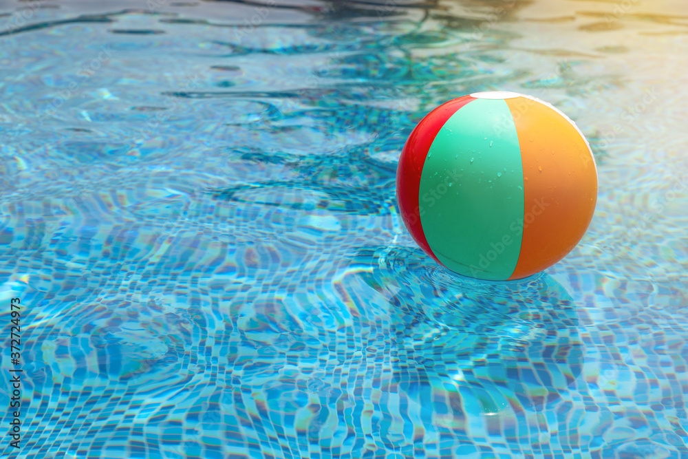 Beach ball in pool. Colorful inflatable ball floating in swimming pool, summer vacation concept.