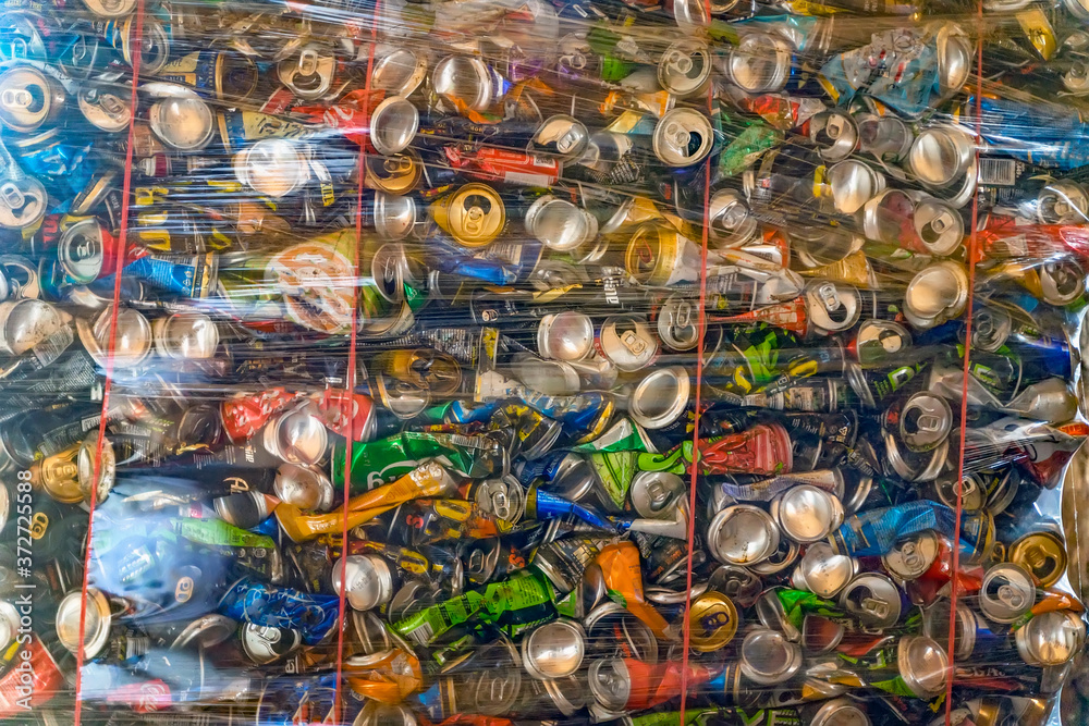 Abstract background of colorful compressed aluminium cans in container stored for recycling. Concept of recycling, ecology, environmental pollution