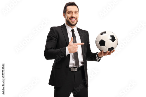 Professional man in a black suit holding a soccer ball and pointing