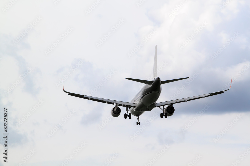 Fototapeta premium white passenger plane comes in to land with natural background of white clouds and blue sky