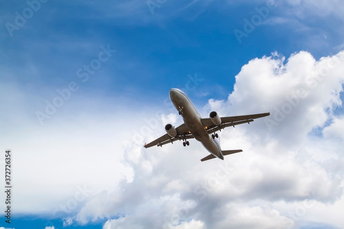 white passenger plane comes in to land with natural background of white clouds and blue sky