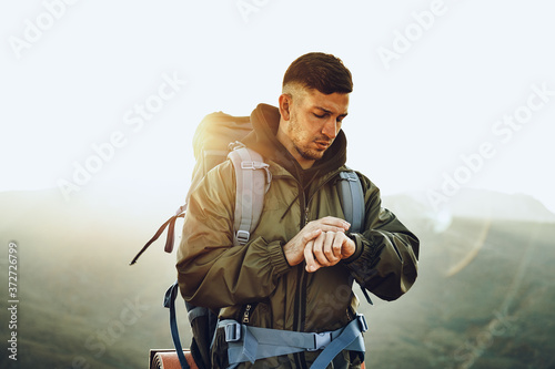 Fototapet Young male traveler looking at his smart watch