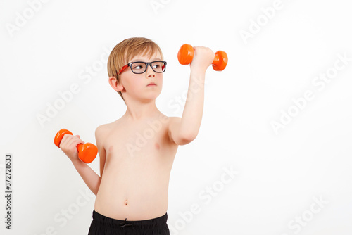 Kid exercising with dumbbells in health sporty club. Healthy childhood, lifestyle.