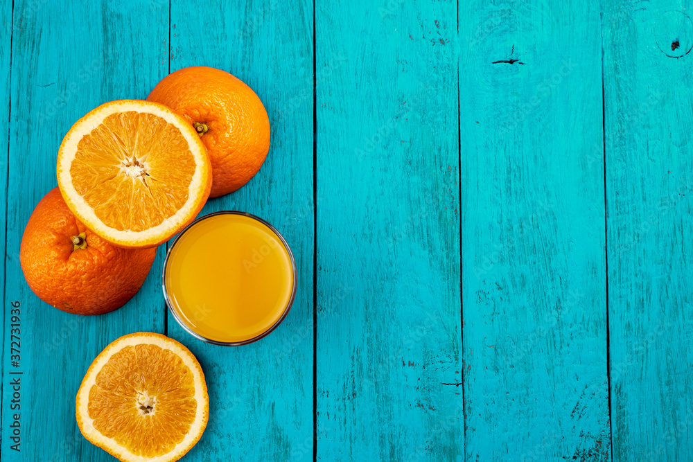 Glass of orange juice on wooden table with fresh sliced fruits of orange. Free space for your text. Top view. Glass of orange juice on wooden table with fresh sliced fruits of orange. Free space for your text. Top view.
