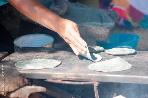 Hands of indigenous women making blue corn tortillas in a traditional way in rustic kitchen
