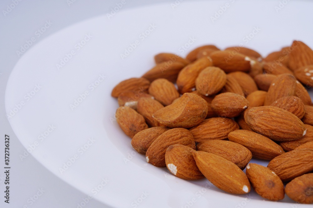 Close up of almonds on white plate. Almond Seeds.
Close up of almonds on white plate. Almond Seeds.