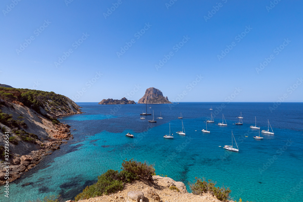 Beautiful panoramic view of the mountain Es Vedra and sea sailing yachts. Ibiza, Balearic Islands, Spain
