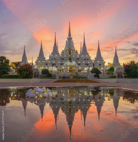 White pagoda or stupa of Asok Maharat buddhist Temple at sunset, Samut Prakan Province, Thailand. Thai architecture. Tourist attraction landmark. photo