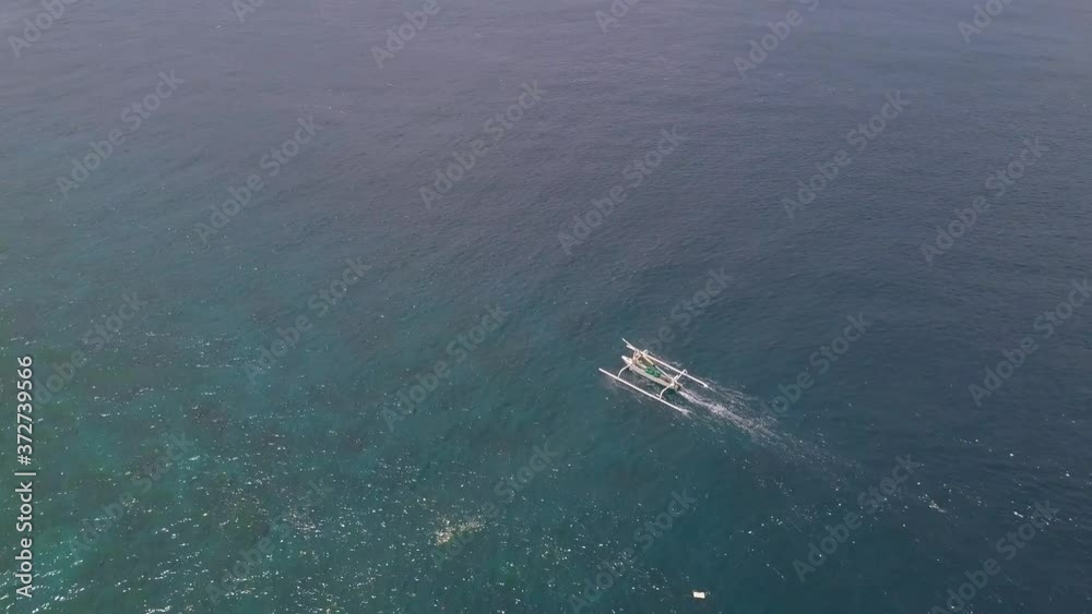 Aerial drone track view of a tourist boat traveling fast in the serene ocean on a sunny day. Bird's eye view to close lower angle. Summer and travel concept. Aerial drone track view of a tourist boat traveling fast in the serene ocean on a sunny day. Bird's eye view to close lower angle. Summer and travel concept.
