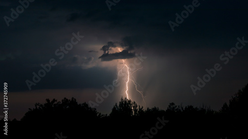 A lightning bolt strikes the ground from a storm cloud at night.