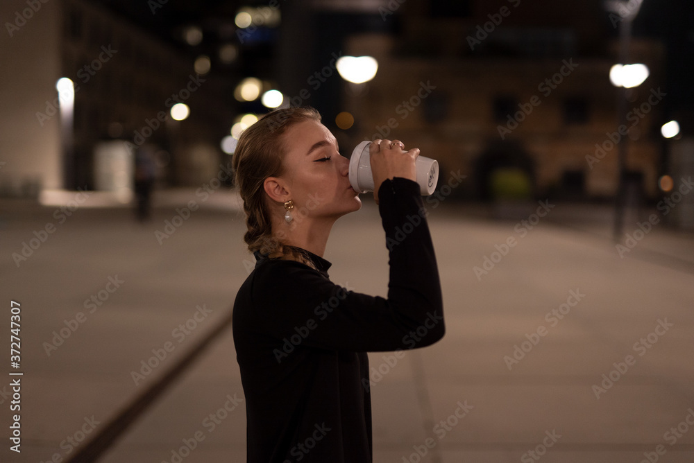 Fototapeta premium Junge Frau mit einem Kaffee in der Hand. Junge Frau mit einem Kaffebecher in der Hand. Junge Frau trinkt einen Kaffe.