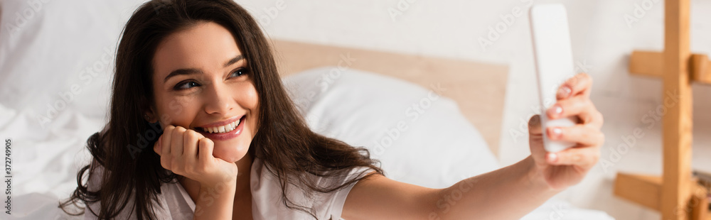 panoramic shot of young woman taking selfie in bedroom panoramic shot of young woman taking selfie in bedroom