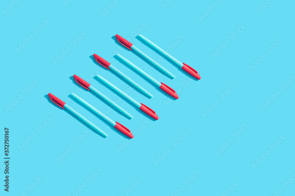 Blue pens with red caps lie on a blue background. The concept of training, business, school, office. Minimalism, copy space.