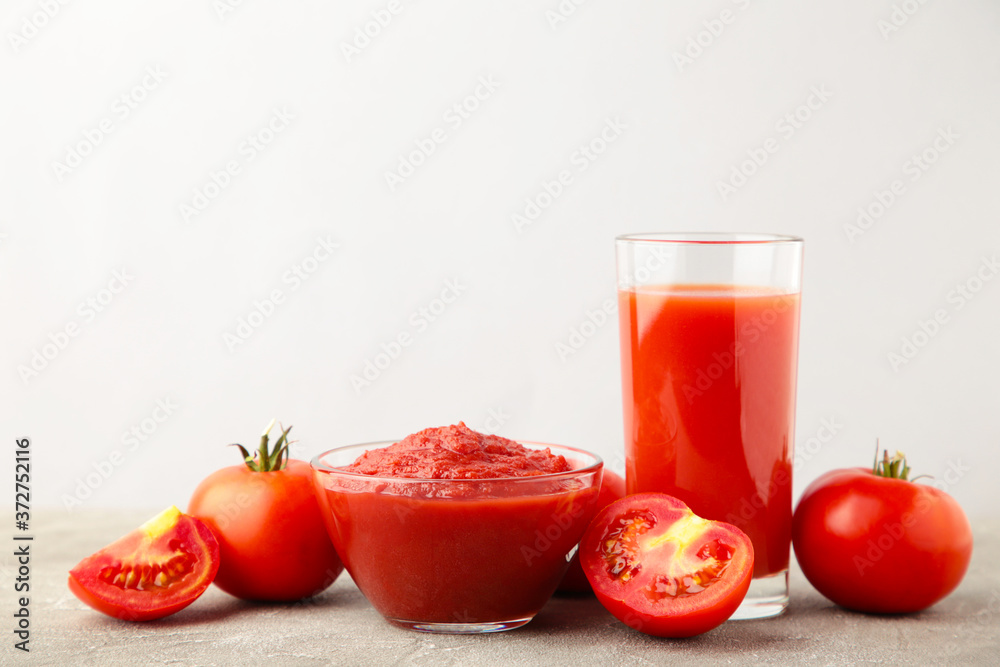 Fresh tomatoes with paste and juice on grey background Fresh tomatoes with paste and juice on grey background
