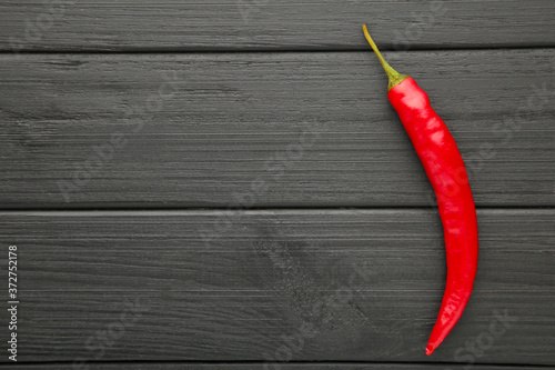 Single red chili pepper on black background