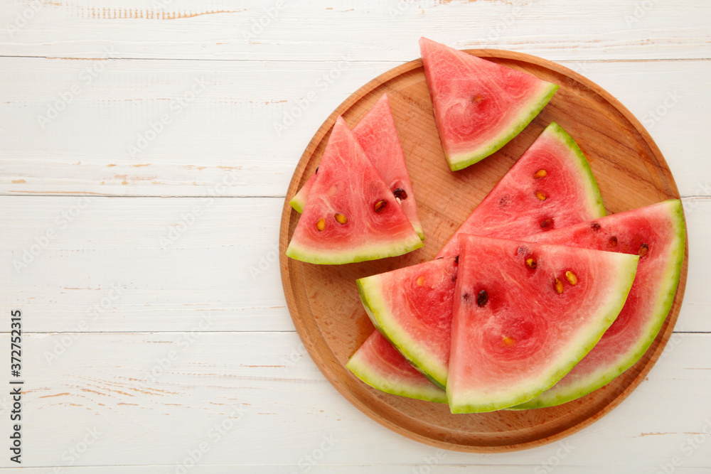 Fresh ripe striped sliced watermelon on cutting board on white wooden background. Fresh ripe striped sliced watermelon on cutting board on white wooden background.