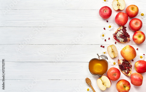 Rosh hashanah (jewish New Year holiday) concept. Traditional symbols. Apples, honey and pomegranates on a white wooden background.