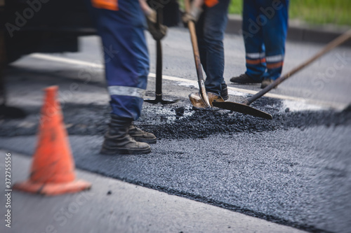 Asphalt paver machine and steam road roller during road construction and repairing works, process of asphalting and paving, workers working on the new road construction site, placing a layer