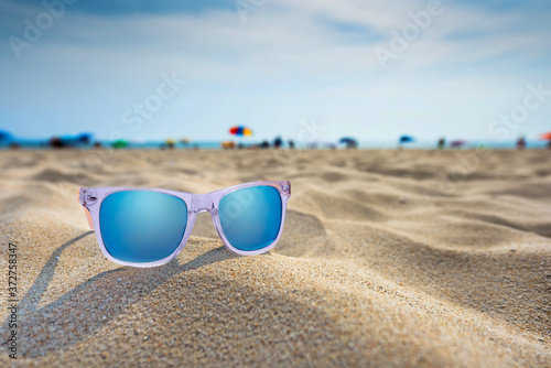 Sun glasses lie on a beach near the sea.