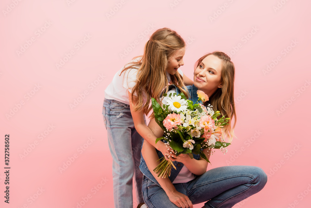 child gifting bouquet of flowers to mom and embracing her isolated on pink child gifting bouquet of flowers to mom and embracing her isolated on pink