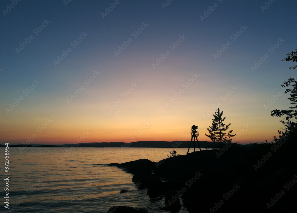 Tripod silhouette on sunset lake in Karelia