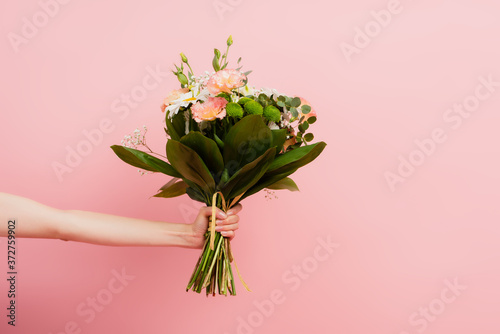 Fotobehang cropped view of female hand with bouquet of flowers isolated on pink
