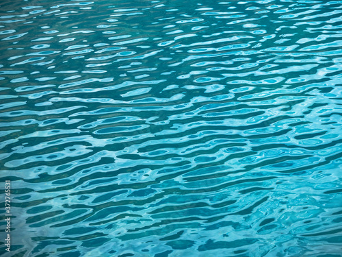 Rippled water texture with soft waves of blue color. Natural background of sea or lake surface