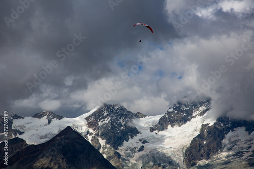 A paraglider sails over the Ober Gabelhorn (4063 m). It is a mountain in the Pennine Alps in Switzerland, located between Zermatt and Zinal.