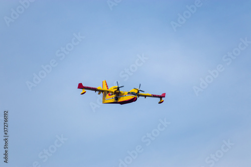 Close up of a fire fighting water bomber airplane flying over head, dropping water on wildfires in Croatia. Flying slowly with its boat shaped hull