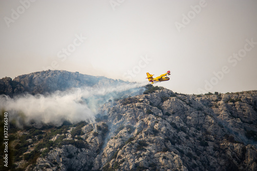 A fire fighting water bomber dropping water on a forest fire on top of the Kozjak mountain in Croatia. Summer wildfires are very common in the dry and warm area of meditarranean
