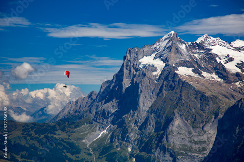 A para glider soars above the village of Grindelwald nedxt to the Wetterhorn mountain in the Swiss Alps. photo