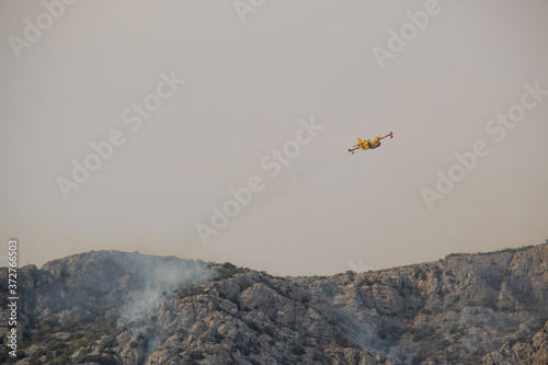 A fire fighting water bomber dropping water on a forest fire on top of the Kozjak mountain in Croatia. Summer wildfires are very common in the dry and warm area of meditarranean