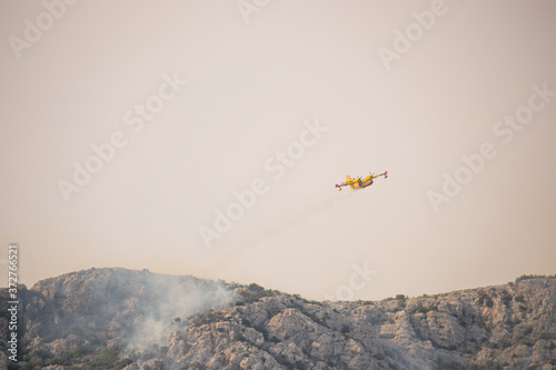 A fire fighting water bomber dropping water on a forest fire on top of the Kozjak mountain in Croatia. Summer wildfires are very common in the dry and warm area of meditarranean