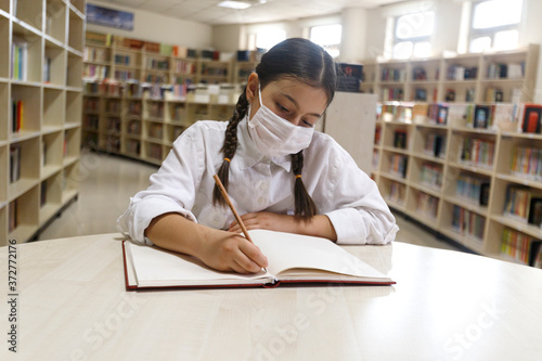 student working in the library with a face mask. 