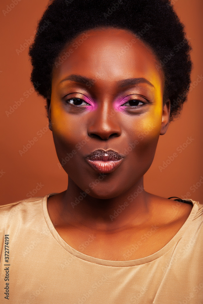 pretty young african american woman with curly hair posing cheerful gesturing on brown background, lifestyle people concept pretty young african american woman with curly hair posing cheerful gesturing on brown background, lifestyle people concept