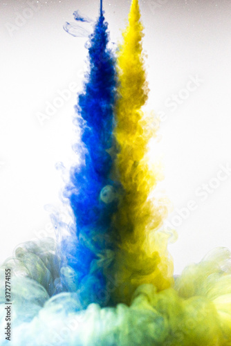 A cloud of yellow and blue paint released into clear water. Isolate on a white background.