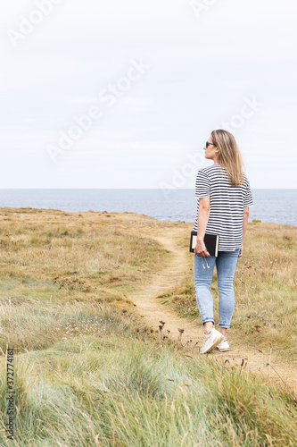 Woman walking along a path in front of the sea