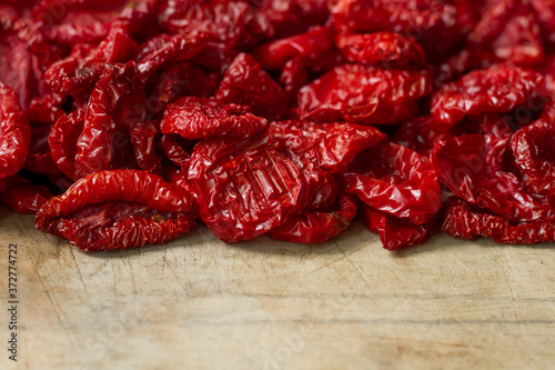 Close-up sun-dried tomatoes with spices and olive oil on wooden cutting board, background or concept, selective focus