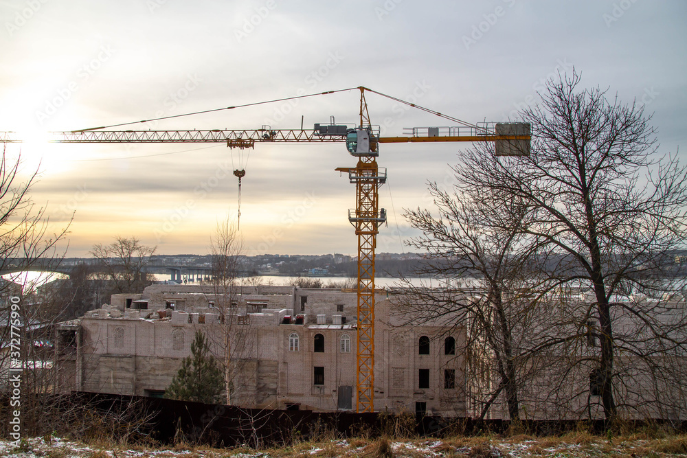 Construction of a building on the river Bank against the sunset. Work on the crane. Construction of a building on the river Bank against the sunset. Work on the crane.