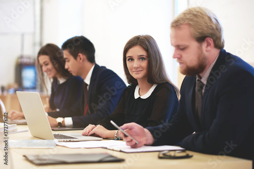 Businesswoman is posing during work on laptop computer and her partner near is chatting on mobile phone. Young students are using net-book and cell telephone to preparing for classes at the university